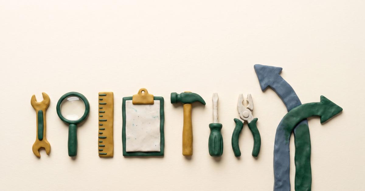 Seven small clay tools laid out in a row on cream paper, beside a clay arrow splitting one path into two