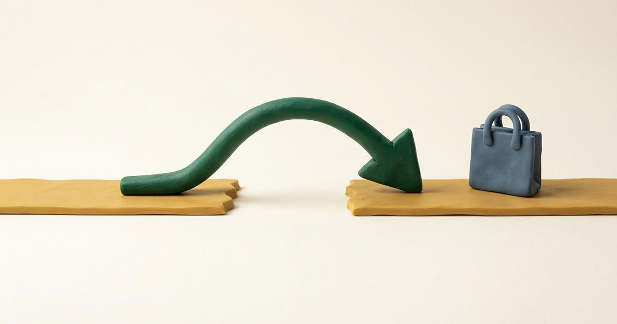 A clay gold road ends at a gap, and a forest green clay arrow curves over it onto the road that continues, where a blue clay shopping bag stands